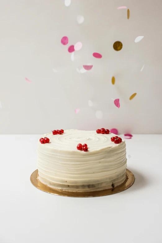 a white cake sitting on top of a wooden plate, red and white, lighthearted celebration, 3 / 4 wide shot, ermine