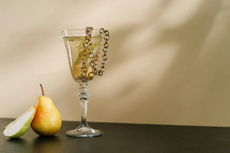 a glass of wine and a pear on a table, inspired by Hedda Sterne, renaissance, neck chains, cocktail bar, clear glass, ignant