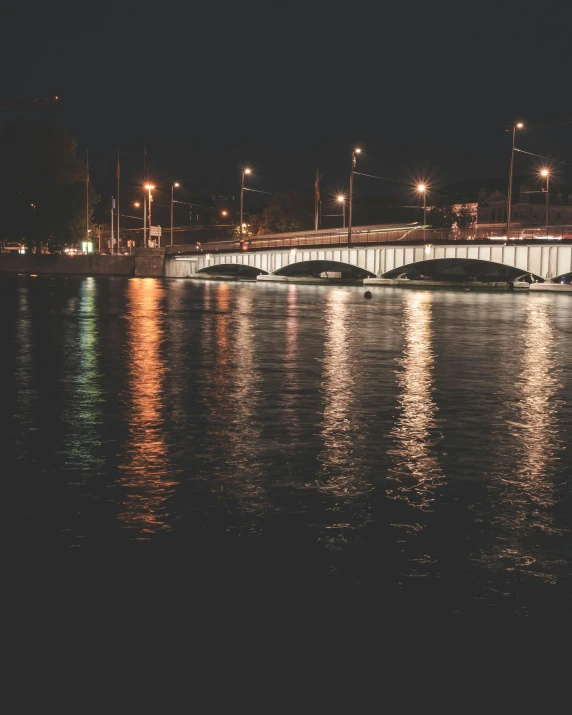 a bridge over a body of water at night, in the middle of the city