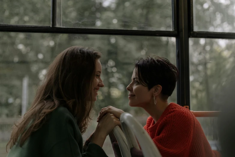 a couple of women sitting next to each other, pexels contest winner, realism, film still promotional image, looking out the window, smiling at each other, ( ( theatrical ) )