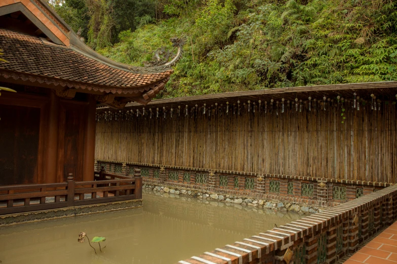 a small pond filled with water next to a wooden fence, inspired by Tōshi Yoshida, unsplash, mingei, las pozas, brown, covered, grey