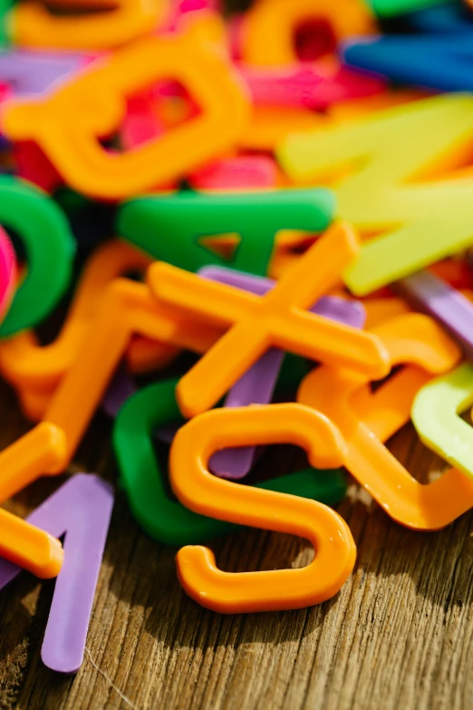 a pile of colorful plastic letters sitting on top of a wooden table, thumbnail, monogram, slides