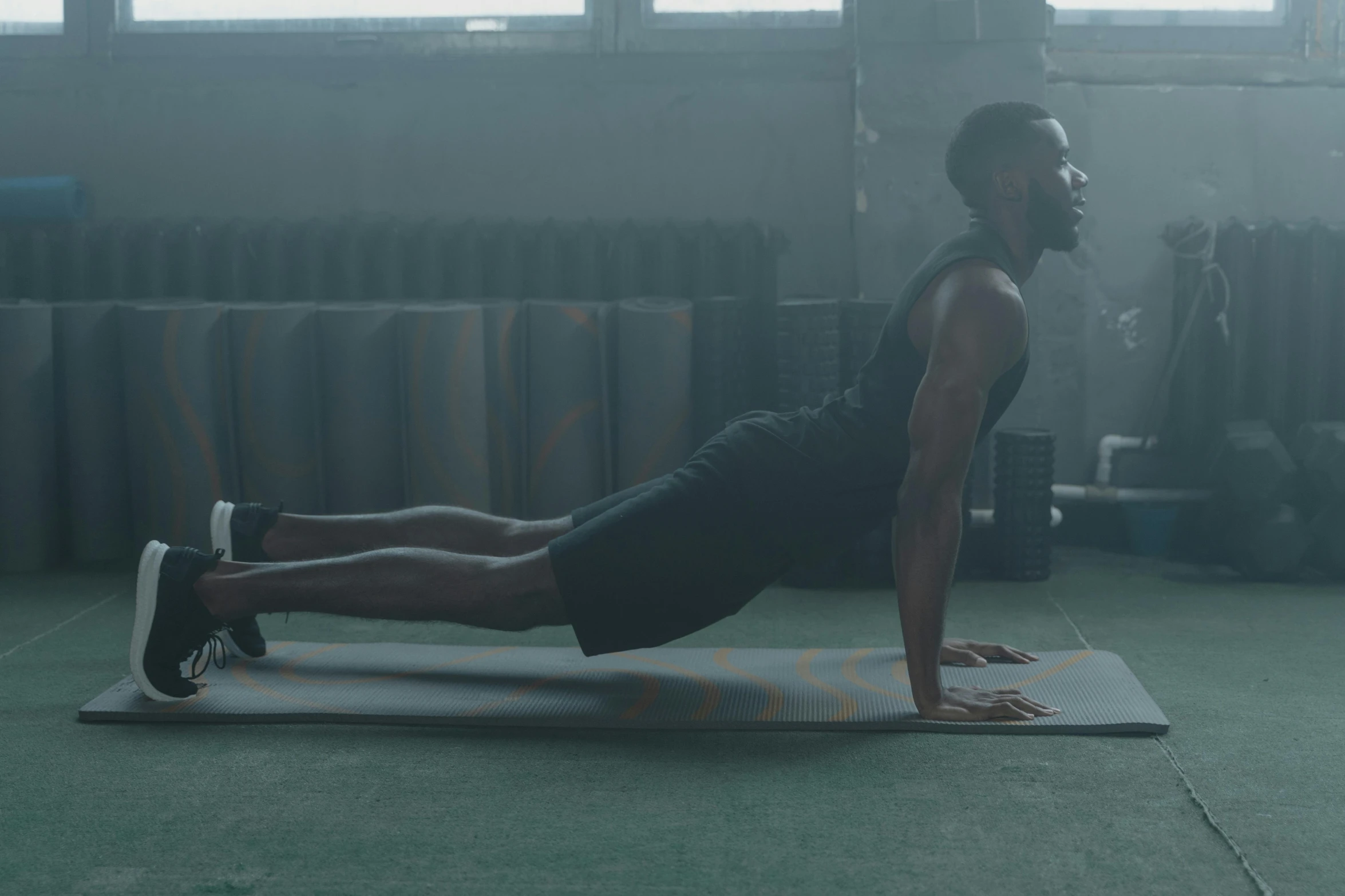 a man doing push ups on a mat in a gym, pexels contest winner, vfx render, black man, dark taint :: athletic, hazy