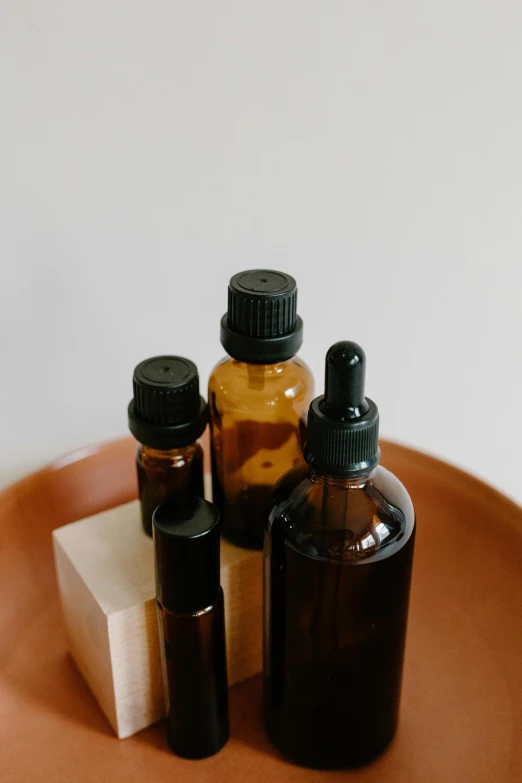 a couple of bottles sitting on top of a brown plate, unsplash, skincare, oils, handcrafted, trending photo