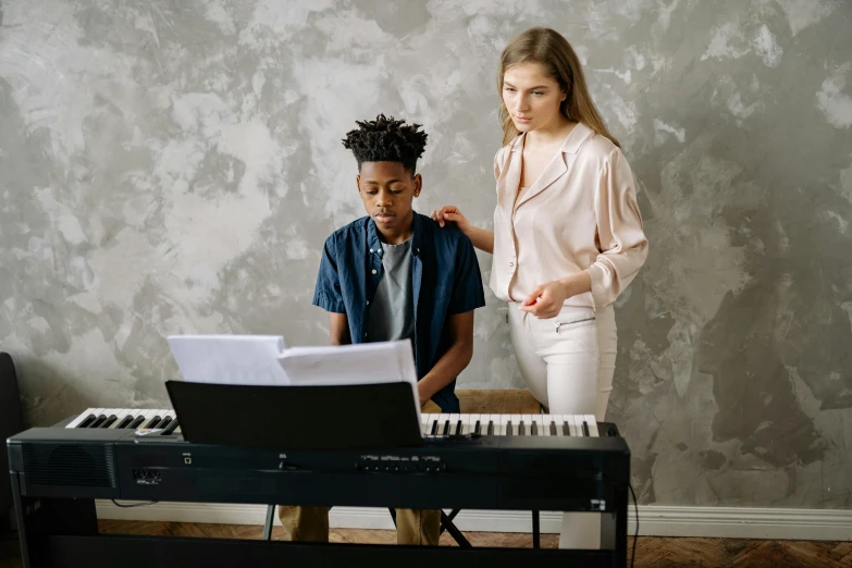 a woman teaching a boy how to play the piano, by Everett Warner, trending on pexels, antipodeans, brown, people at work, on a gray background, student