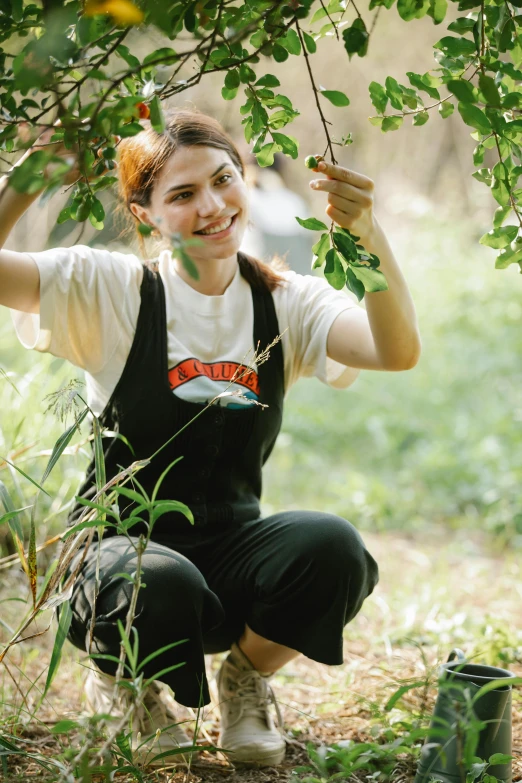 a woman crouches down to pick fruit from a tree, a portrait, inspired by Elsa Bleda, renaissance, greta thunberg smiling, promo still, wearing overalls, woman with cat ears