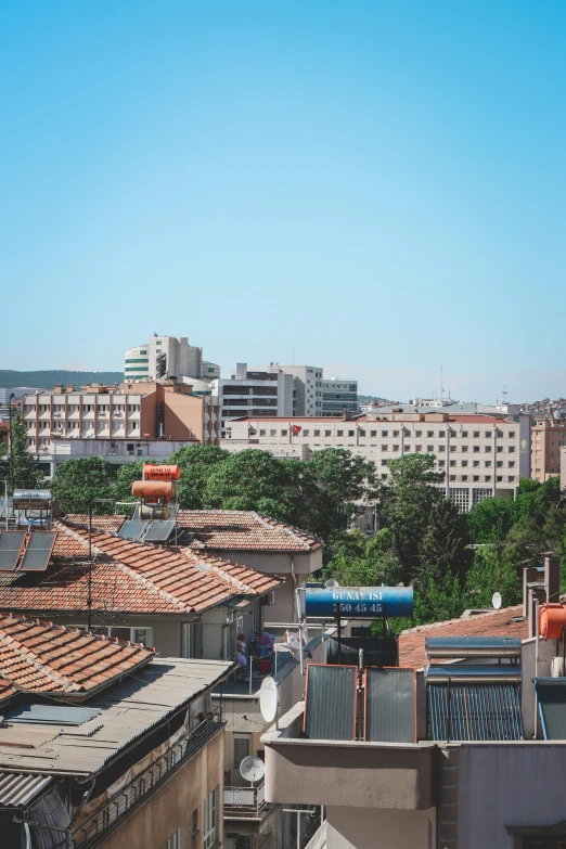 a view of a city from the top of a building, can basdogan, trees in background, midday photograph, square