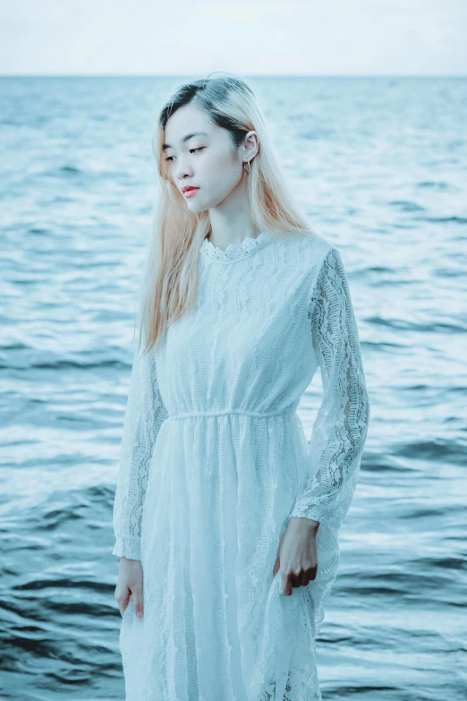 a woman standing in front of a body of water, an album cover, inspired by Elsa Bleda, unsplash, romanticism, white hanfu, lace dress, jaeyeon nam, ☁🌪🌙👩🏾