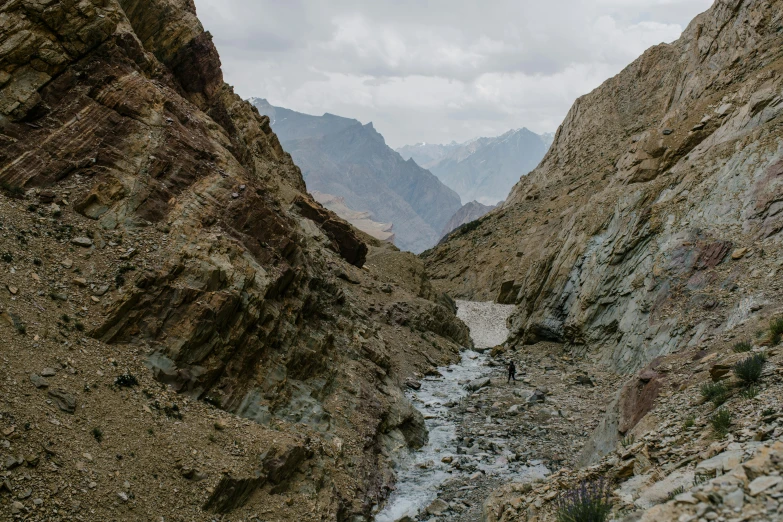 a stream running through a rocky canyon with mountains in the background, a portrait, inspired by Steve McCurry, pexels contest winner, les nabis, cinematic silk road lanscape, thumbnail, india, slight overcast