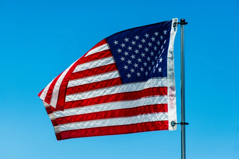 an american flag flying high in the sky, by Jan Rustem, unsplash, three quarter view, side profile view, shot on sony a 7, blue clear skies