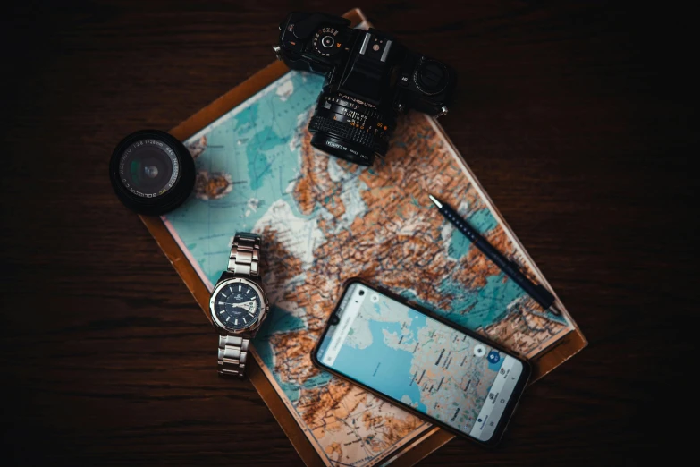 a cell phone sitting on top of a map next to a camera, a picture, watch photo, 1 2 9 7, travel, jewelry