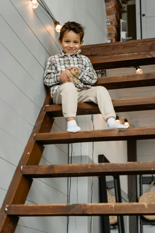 a little boy that is sitting on some stairs, sitting on top a table