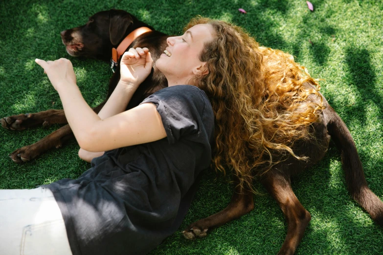 a woman laying on the grass with her dog, pexels contest winner, jen atkin, wavy hair spread out, profile image, smiling down from above