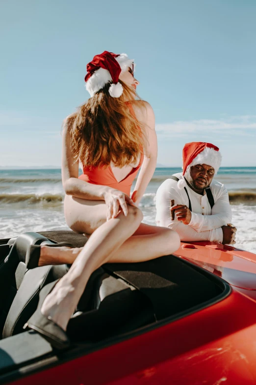 a woman in a bikini sitting on top of a red car, pexels contest winner, wearing a santa hat, man grabbing a womans waist, oceanside, tyler the creator