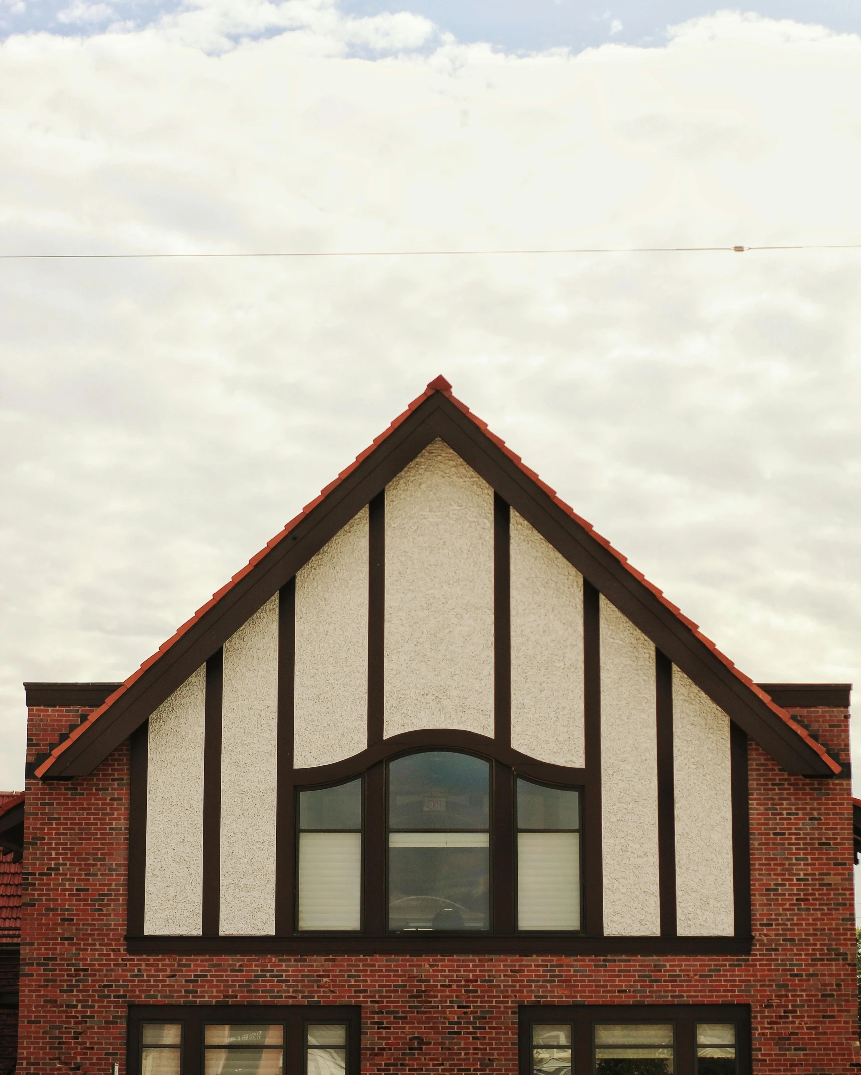 a red fire hydrant sitting in front of a brick building, an album cover, unsplash, arts and crafts movement, clouds outside the windows, symmetrical front view, gambrel roof, pointed arches