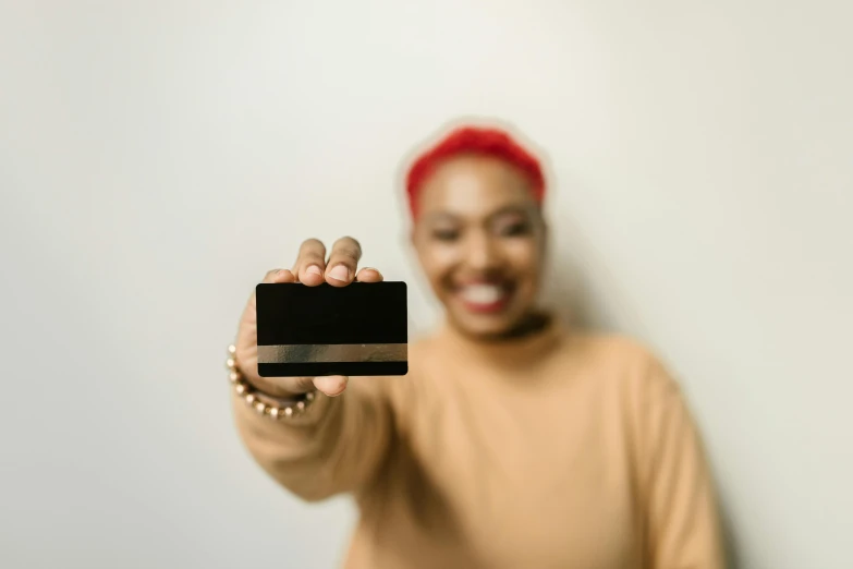 a woman holding a credit card in front of her face, pexels contest winner, renaissance, black main color, panel of black, while smiling for a photograph, small