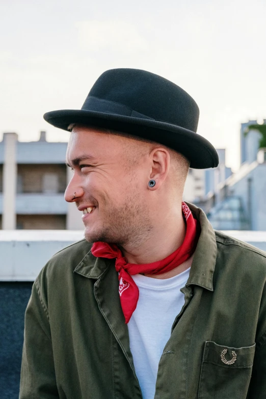 a man wearing a black hat and a green jacket, an album cover, inspired by Niko Henrichon, unsplash, neo-dada, he‘s wearing a red neckerchief, in a rooftop, vitaliy bondarchuk, smiling slightly