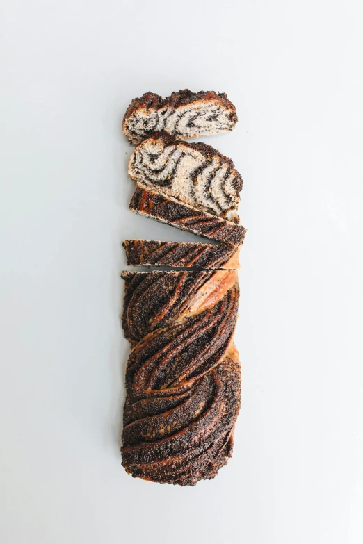 a piece of bread sitting on top of a white table, arabesque, tiger stripes, made of tar, vine twist, whole-length