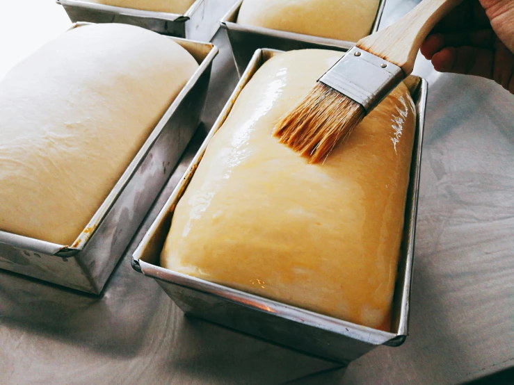 a person using a brush to paint a loaf of bread, by Julia Pishtar, unsplash, in a row, baking a cake, australian, ginormous