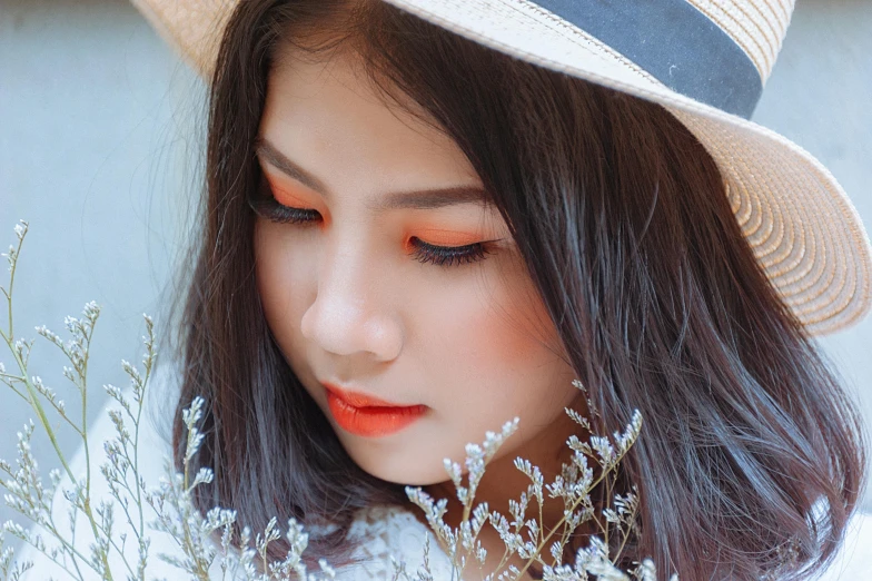 a woman wearing a hat and holding a bunch of flowers, inspired by Itō Shinsui, trending on pexels, aestheticism, white and orange, wearing eye shadow, asian girl, closeup photograph