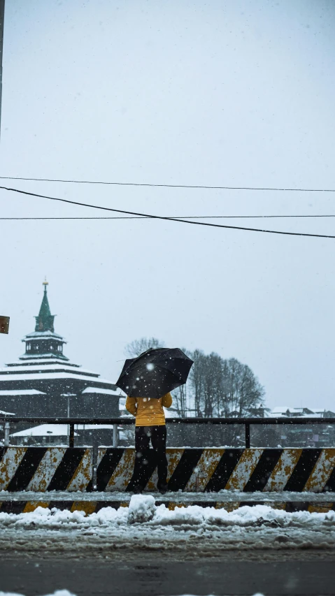 a person walking in the snow with an umbrella, by Tobias Stimmer, building in the distance, tula, low quality photo, aomori japan