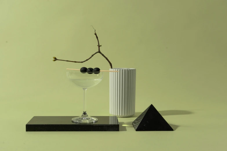 a martini sitting on top of a table next to a vase, a still life, inspired by Carlo Martini, unsplash, suprematism, miniature porcelain model, ashford black marble sculpture, videogame still, detailed product image