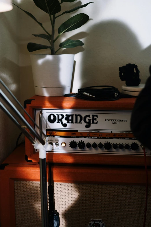 an orange amp sitting on top of a table next to a plant, inspired by Elsa Bleda, low quality photo, indie, 90s photo, studio lights