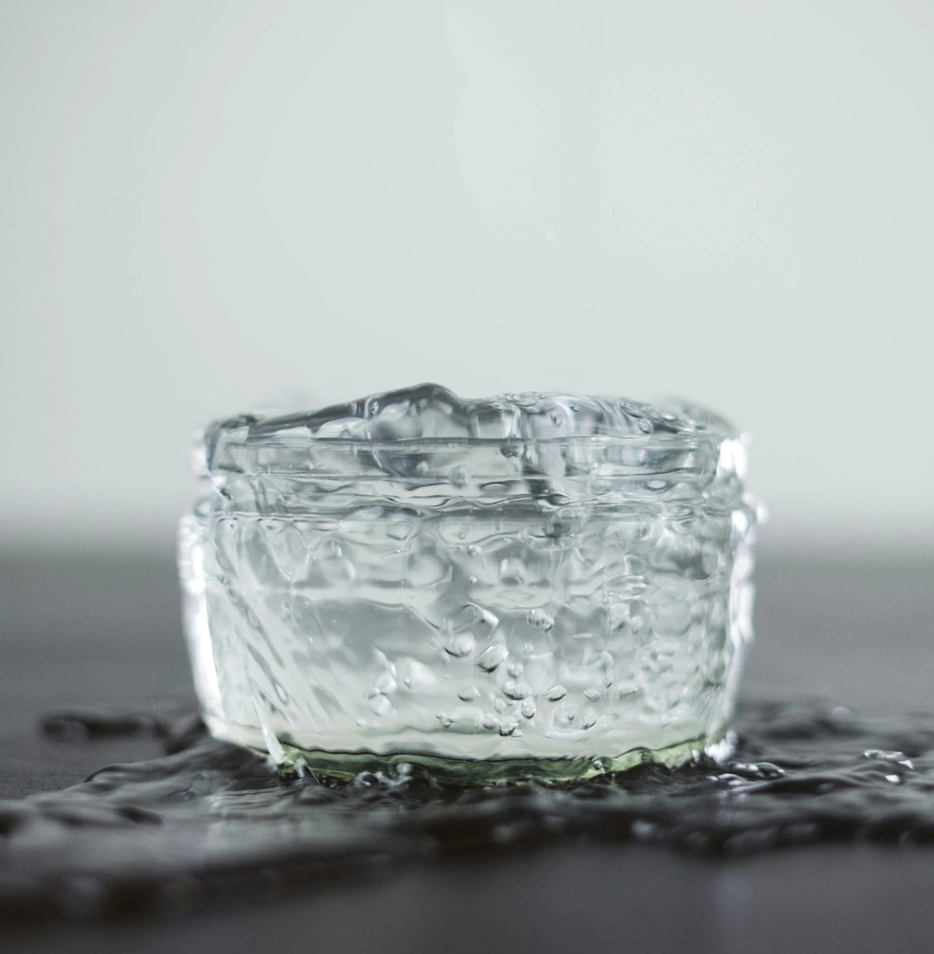 a glass of water sitting on top of a table, by Daniel Seghers, pexels, hyperrealism, jelly - like texture, glass jar, bubbling skin, high quality product photo