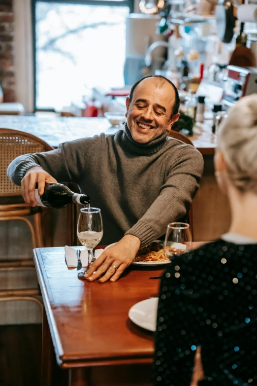 a couple of people that are sitting at a table, holding wine bottle, serving suggestion, profile image, lachlan bailey