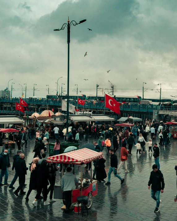 a crowd of people walking across a wet street, a colorized photo, pexels contest winner, hurufiyya, turkish and russian, fish market stalls, while it's raining, red flags holiday