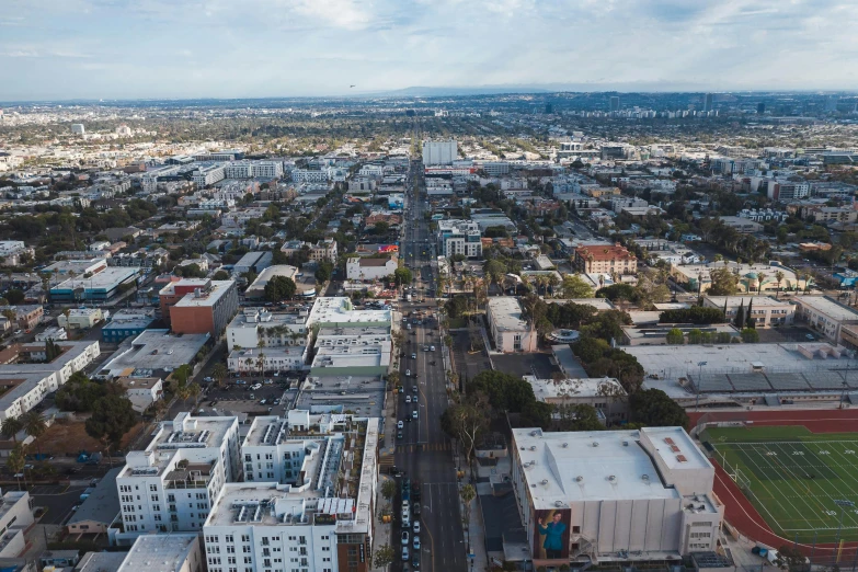 an aerial view of a city with a soccer field, by Marshall Arisman, unsplash, long beach background, skies behind, hollywood, photograph of the city street