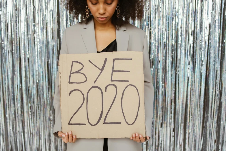 a woman holding a sign that says bye 2020, trending on pexels, happening, post graduate, an olive skinned, 2 0 s, k