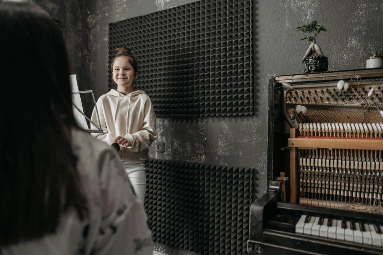 a woman standing in front of a piano, trending on pexels, two women, background image, studio recording, an escape room in a small