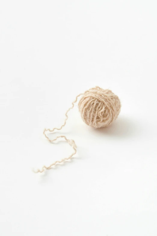 a ball of yarn sitting on top of a white surface, by Tsuruko Yamazaki, official product photo, beige, looping, vanilla
