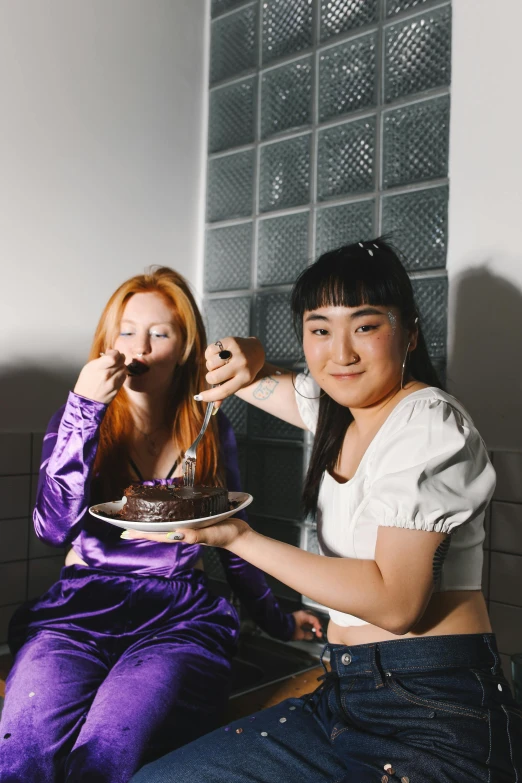 a couple of women sitting next to each other, an album cover, inspired by Wang Duo, trending on pexels, renaissance, eating cakes, half asian, pals have a birthday party, purple