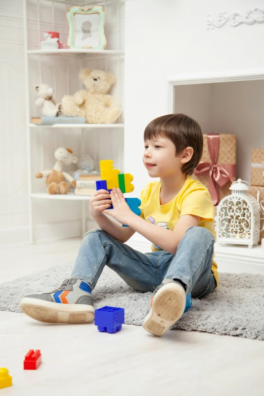 a little boy sitting on the floor playing with blocks, a picture, by Dan Content, shutterstock, blue theme and yellow accents, toy room, young teen, friends
