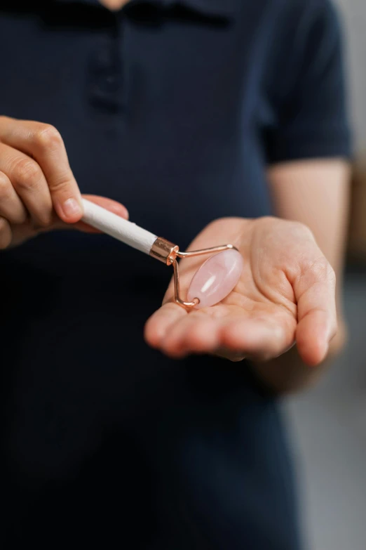 a person holding a cigarette in their hand, rose quartz, with electric arc device, sculpting, healing pods