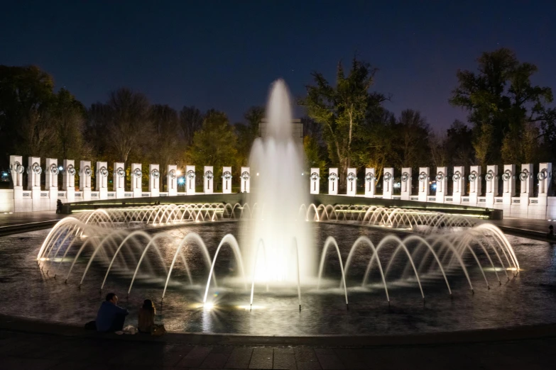 the world war ii memorial is lit up at night, pexels contest winner, visual art, white stone arches, promo image, gardens and fountains, beautiful sunny day