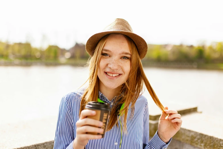 a girl in a hat holding a cup of coffee, trending on pexels, happening, flowing ginger hair, greta thunberg smiling, her hair is tied above her head, teenager