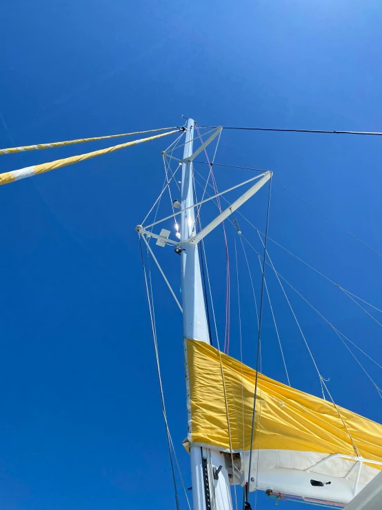 the mast of a sail boat against a blue sky, by Sven Erixson, yellow awning, photograph taken in 2 0 2 0, view from ground, tall