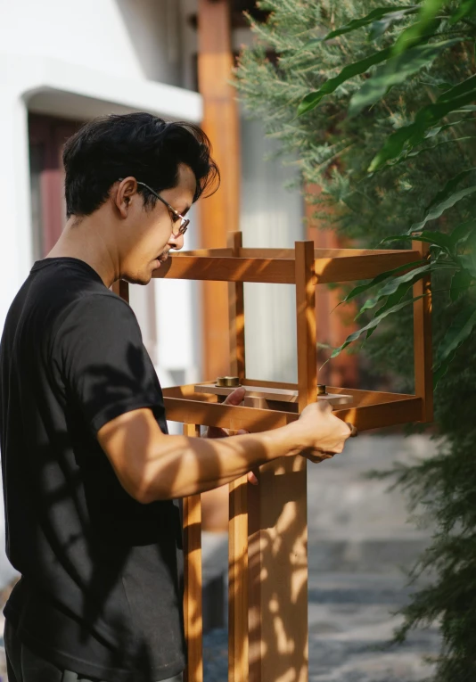 a man standing in front of a wooden structure, a hyperrealistic painting, inspired by Yeong-Hao Han, pexels contest winner, visual art, carrying a tray, tranding on art station, headshot profile picture, sunny day time