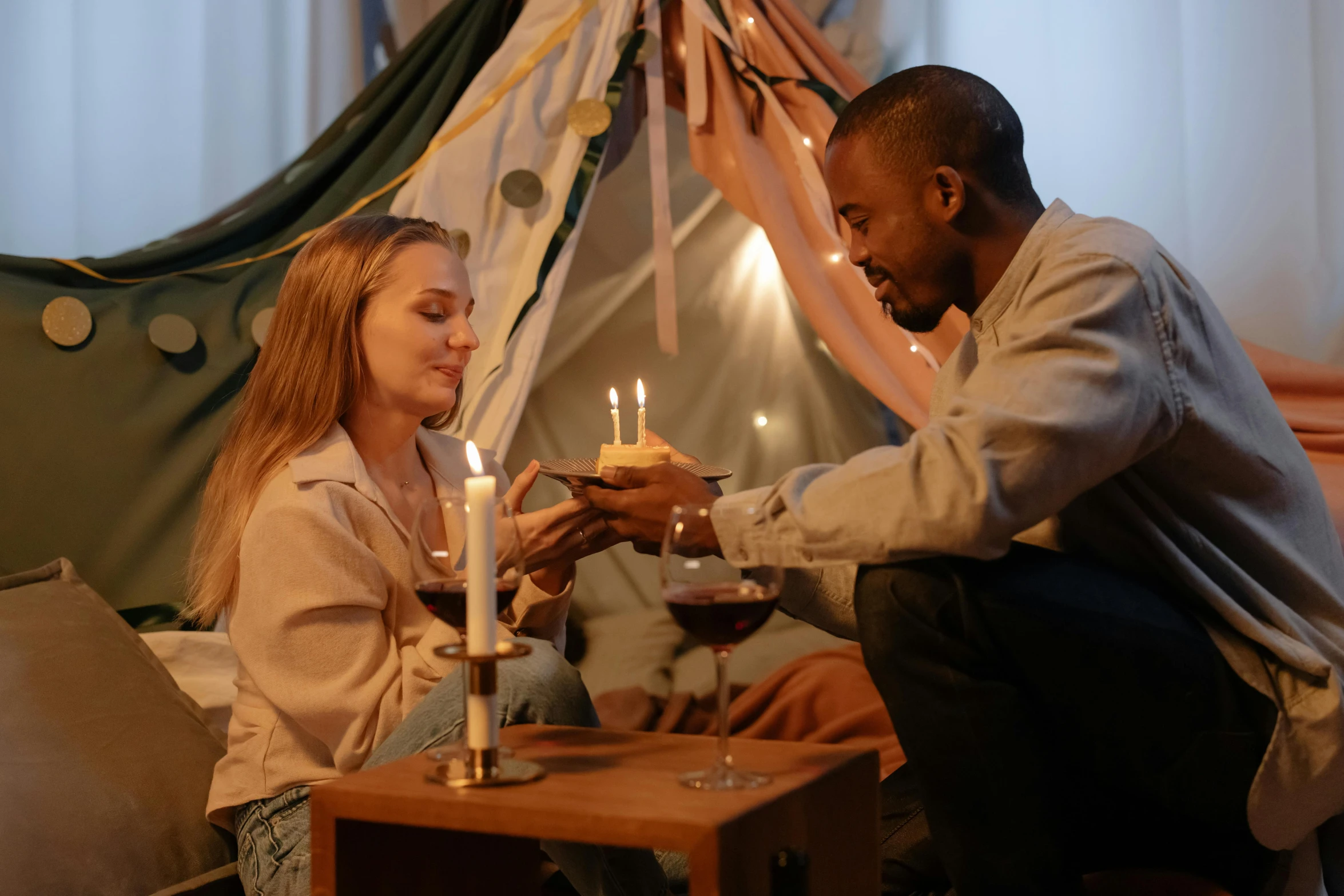 a man and a woman sitting at a table with candles, pexels contest winner, tickle fight in the death tent, holding a birthday cake, brown, grey