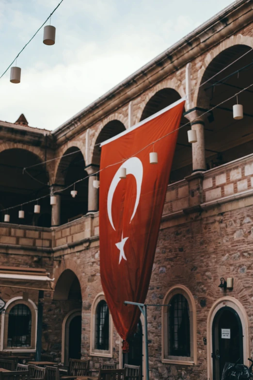 a large red flag hanging from the side of a building, inspired by Yasar Vurdem, hurufiyya, background image, brown, square, turkey