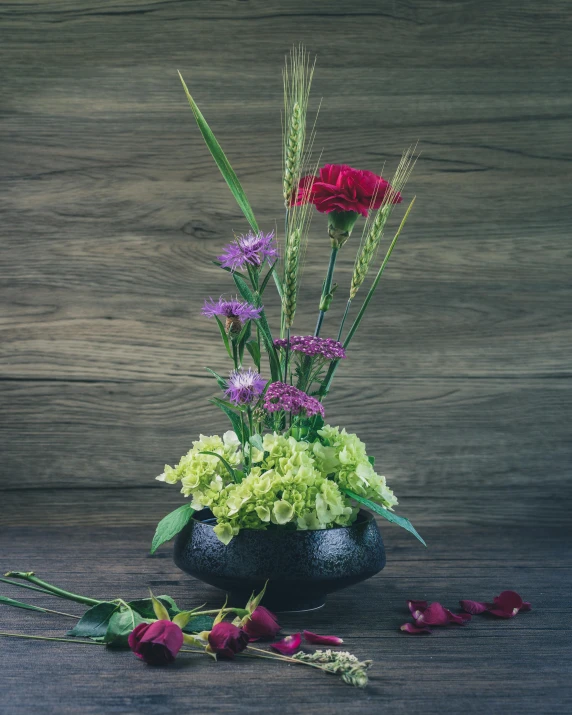 a vase filled with flowers sitting on top of a wooden table, black and green scheme, purple and scarlet colours, award-winning, high quality product photo