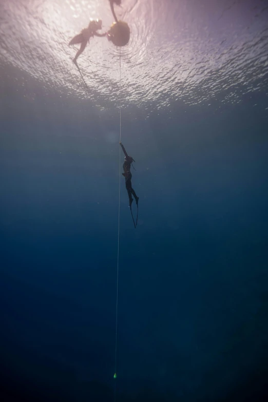 a couple of people that are in the water, a picture, by Robert Jacobsen, hanging rope, deep blue atmosphere, award - winning photograph, ignant
