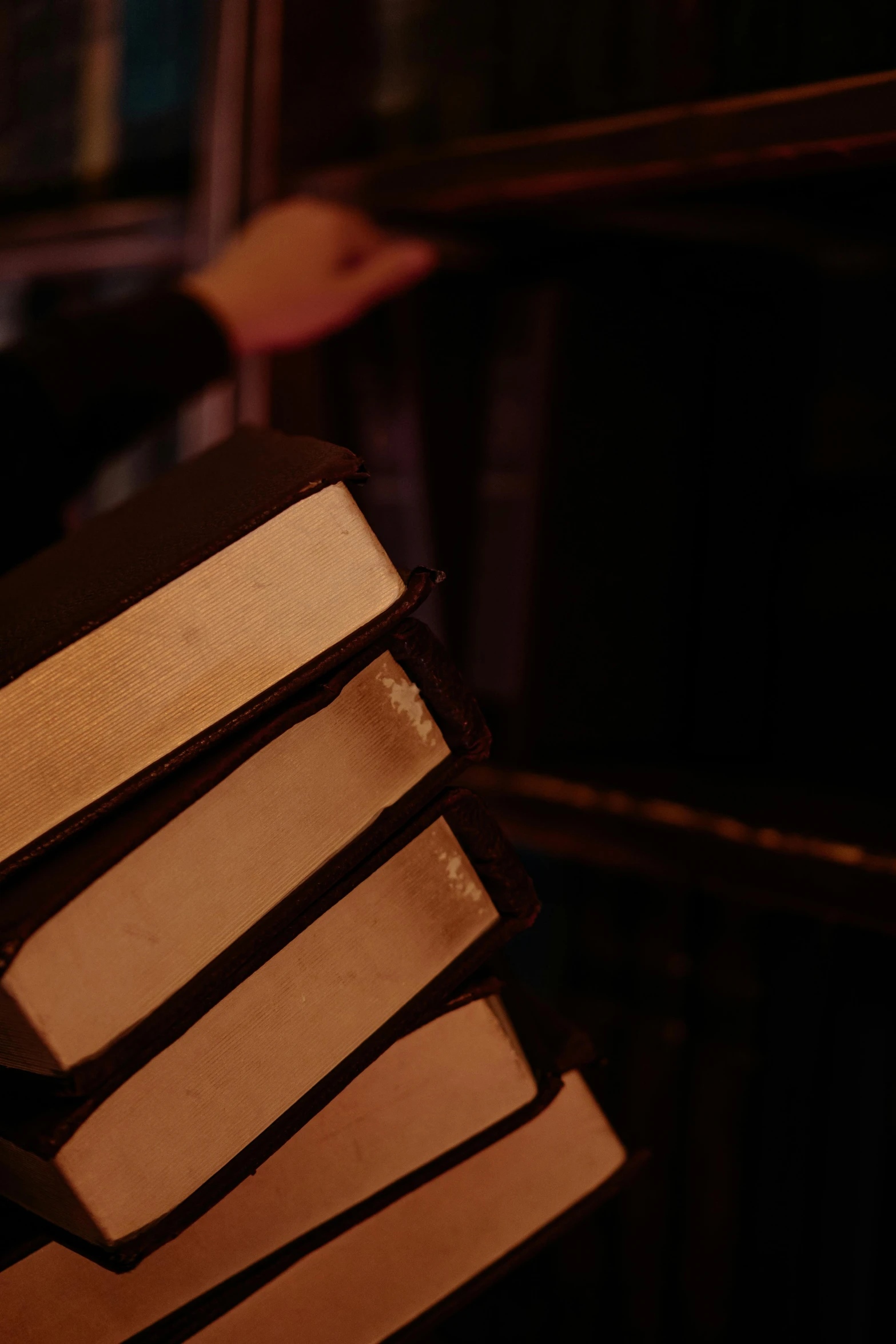 a person holding a stack of books in front of a window, an album cover, by David Donaldson, unsplash, dark and dim lighting, theatre equipment, server in the middle, chocolate