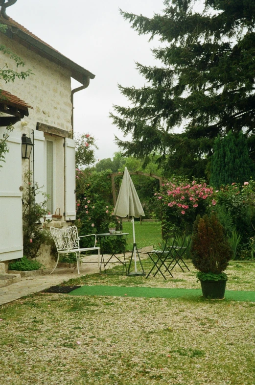 a couple of chairs sitting on top of a lush green field, french village exterior, lawns, lots de details, flowery cottage