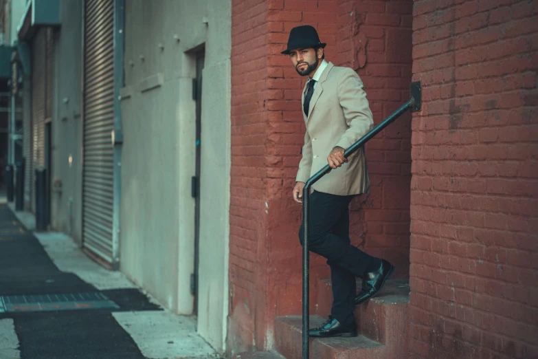 a man in a suit and hat leaning against a brick wall, inspired by Vincent Lefevre, pexels contest winner, harlem renaissance, coming down the stairs, a portrait of rahul kohli, vintage color, full-body-shot