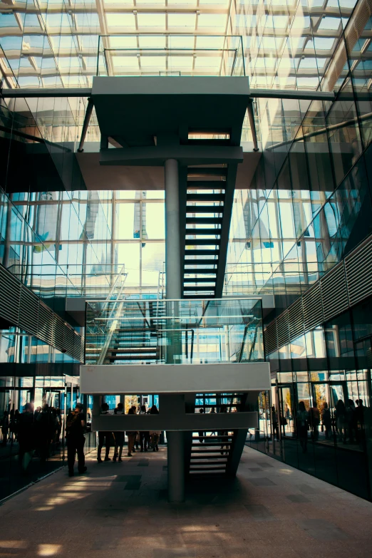 a group of people walking inside of a building, lots of glass details, anamorphic cinematography, colour corrected, large staircase