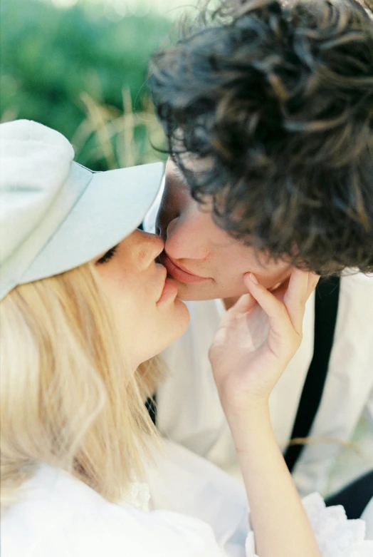 a couple of people that are kissing each other, white hat, pale skin curly blond hair, zoomed in shots, portra 160